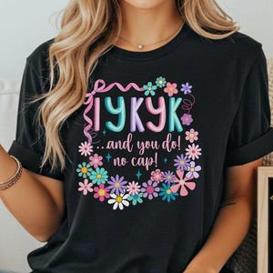 May include: Black t-shirt with a floral design and the text "IYKYK...and you do! no cap!". A small chalkboard displays the text "I believe in you!" with a star and lightbulb graphic.