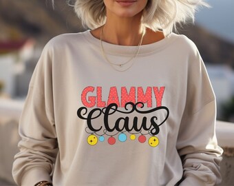May include: A beige sweatshirt with the text "Glammy Claus" in black and red lettering with a string of colorful Christmas lights underneath.