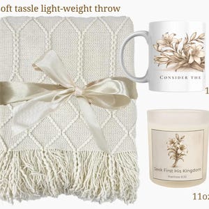 May include: A cream-colored, lightweight throw blanket with a diamond pattern and tassel fringe, tied with a satin ribbon. Includes an 11oz mug and candle, both with floral designs and text that reads "Consider the" and "Seek First His Kingdom".