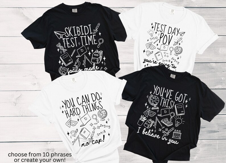 Puede incluir: Cuatro camisetas, dos negras y dos blancas, con gr&aacute;ficos y texto con tem&aacute;tica escolar. Las camisetas presentan frases como "Skibidi Test Time" y "You've Got This!" con ilustraciones de &uacute;tiles escolares. El texto "choose from 10 phrases or create your own!" est&aacute; en la parte inferior.