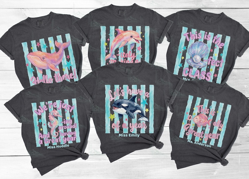 May include: Six charcoal gray t-shirts featuring ocean-themed graphics with light blue vertical stripes, colorful stars, and text including Hello there, This is the -fect CLASS, We're just -ing around, Let's have a of a year, and This is a great year.
