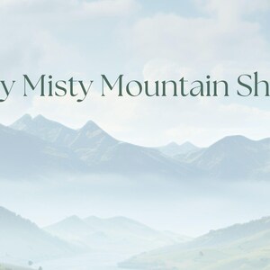 May include: A scenic landscape featuring a mountain range shrouded in mist under a cloudy sky. The text "My Misty Mountain Shop" is displayed in elegant, dark green lettering, suggesting a nature-themed business or product.