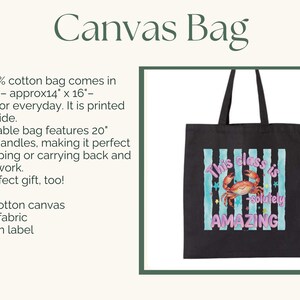 May include: A black canvas tote bag with two shoulder straps. The front features a graphic of a crab centered over vertical light blue and white stripes, surrounded by small stars. The text reads: This class is -solutely AMAZING.