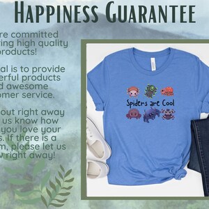 Pode incluir: Uma camiseta azul clara com a frase "Spiders are Cool" e ilustra&ccedil;&otilde;es de v&aacute;rias aranhas. A camiseta &eacute; combinada com jeans azuis e t&ecirc;nis brancos. A imagem tamb&eacute;m inclui texto sobre uma garantia de felicidade.