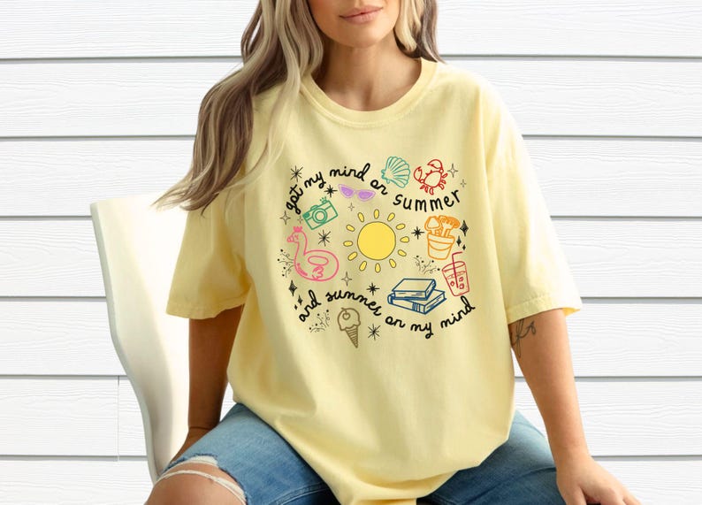 May include: A yellow t-shirt with a graphic design of summer-themed icons and the text "got my mind on summer and summer on my mind".
