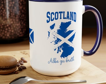 May include: White ceramic mug with a blue rim and handle. The mug features a blue outline of Scotland with a white X inside, and the text "SCOTLAND" and "Alba gu bràth".