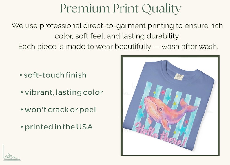 May include: A periwinkle blue t-shirt featuring a graphic of a pink whale swimming over vertical teal stripes and colorful stars. The text "Hello there!" is printed in pink below the whale. The image includes text about premium print quality.