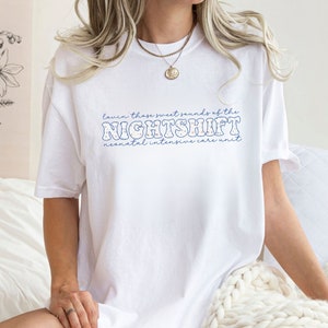 May include: White t-shirt with blue text that reads "Lavin' those sweet sounds of the NIGHTSHIFT neonatal intensive care unit." The shirt has a relaxed fit and is made of a soft material.