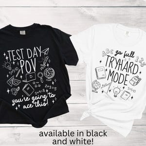 Puede incluir: Dos camisetas, una negra y otra blanca, con gr&aacute;ficos escolares. La camiseta negra dice "TEST DAY POV" con s&iacute;mbolos matem&aacute;ticos y un port&aacute;til. La blanca dice "go full TRYHARD MODE". Disponible en blanco y negro.