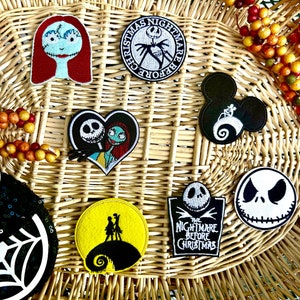 May include: A collection of nine embroidered patches featuring characters from the movie The Nightmare Before Christmas. The patches are on a woven wicker background. The patches include Jack Skellington, Sally, and Zero.
