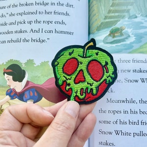 May include: A green apple with a red skull and dripping red icing. The apple is a fabric patch.