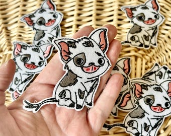 May include: A white embroidered patch featuring a cartoon piglet with black spots, large dark eyes, and pink inner ears. The piglet has a smiling expression with a visible tongue and a thin, curved tail. The patch has a white felt border.