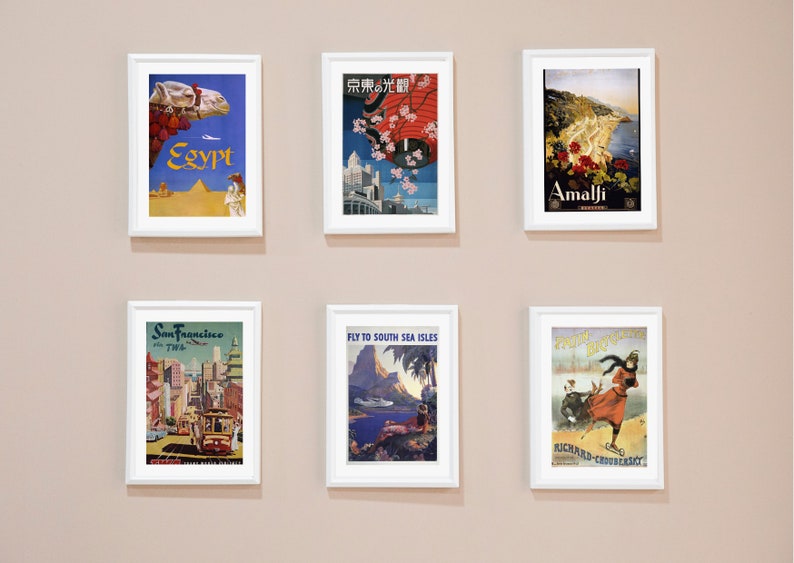 May include: Six vintage travel posters in white frames on a beige wall. The posters feature destinations like Egypt, Tokyo, Amalfi, San Francisco, South Sea Isles, and a winter scene.