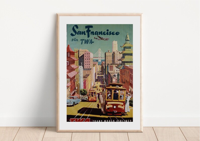 May include: Vintage travel poster advertising a trip to San Francisco via TWA airlines. The poster features a colorful illustration of the city skyline, including the Golden Gate Bridge, cable cars, and buildings. The text "San Francisco via TWA" is prominently displayed at the top of the poster.