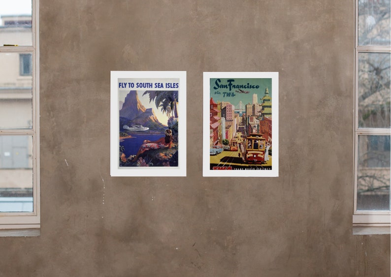 May include: Two vintage travel posters framed in white. The left poster features a tropical island scene with a plane flying overhead and the text "Fly to South Sea Isles". The right poster features a cityscape with a cable car and the text "San Francisco via TWA".