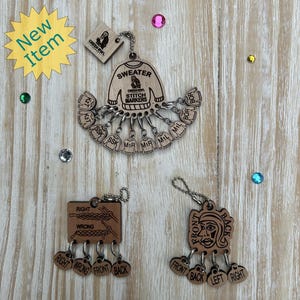 May include: Wooden stitch markers with a sweater design and the text "SWEATER STITCH MARKERS". Additional markers feature knitting diagrams and the words "RIGHT", "WRONG", "FRONT", and "BACK". A "New Item" sticker is in the image.