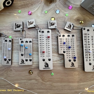 May include: Five wooden counting tools with beads and numbers on them. Each tool has a small owl graphic and the text "GREEN OWL" on it. The tools are hanging from a chain.