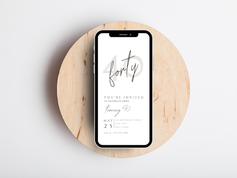 May include: A smartphone displays a digital invitation for a 40th birthday celebration. The invitation features the word "forty" in a stylish script, along with event details. The phone rests on a round, light-colored wooden surface.