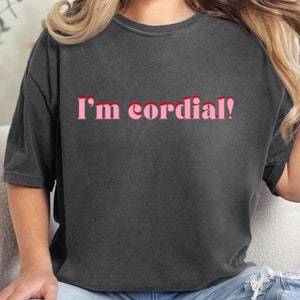 Puede incluir: Una camiseta gris oscuro con el texto "I'm cordial!" en letras rosas.