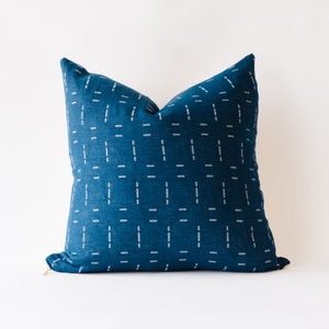 Puede incluir: Una almohada azul turquesa con un patrón geométrico blanco. La almohada tiene una cremallera.