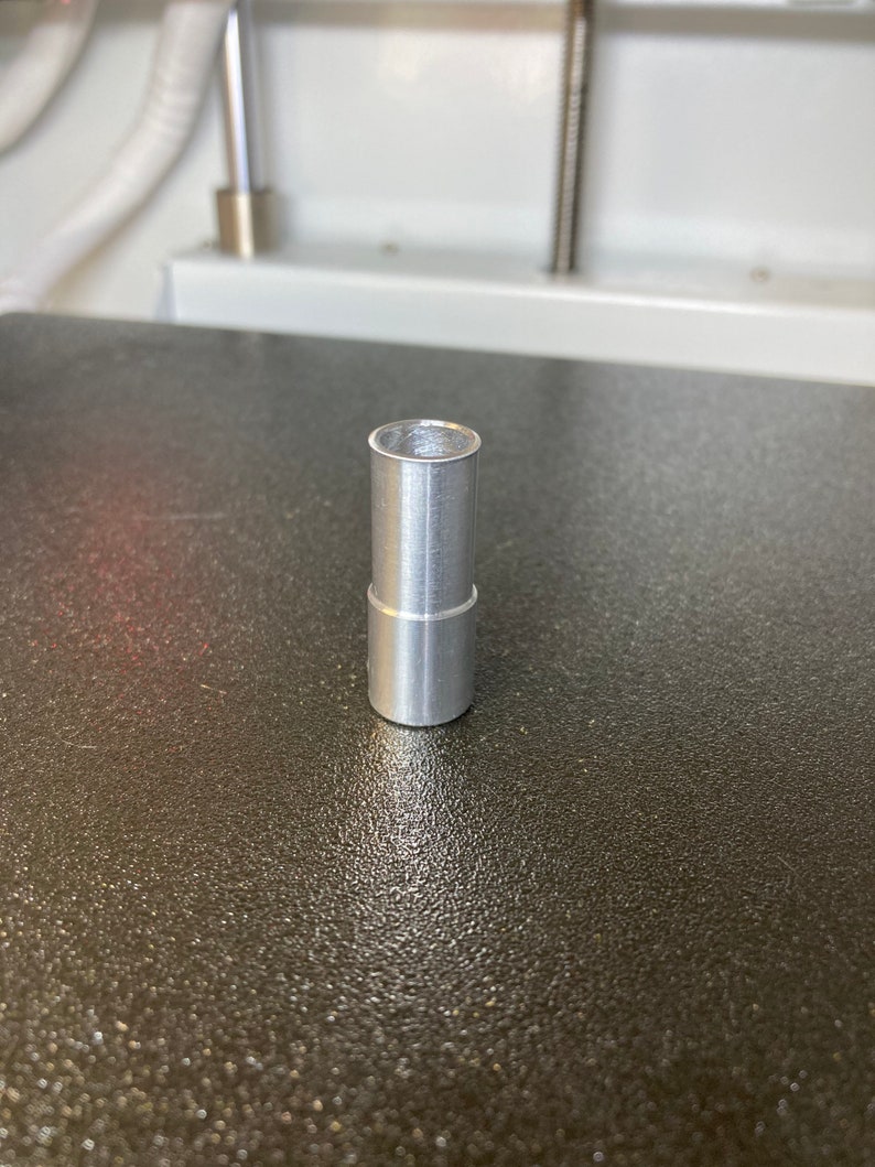 Puede incluir: Un tubo de metal plateado con un acabado liso cepillado. El tubo mide aproximadamente 5 cm de largo y tiene un di&aacute;metro de unos 2,5 cm.