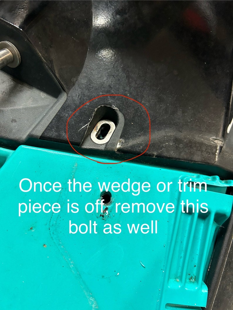 May include: A close-up of a black metal bolt with a silver washer. The bolt is located on a black surface. The bolt is circled in red. The text 'Once the wedge or trim piece is off, remove this bolt as well' is written below the bolt.