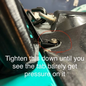 May include: A close-up of a black plastic part with a silver screw. The screw is circled in red. The text 'Tighten this down until you see the tab barely get pressure on it' is visible below the part.
