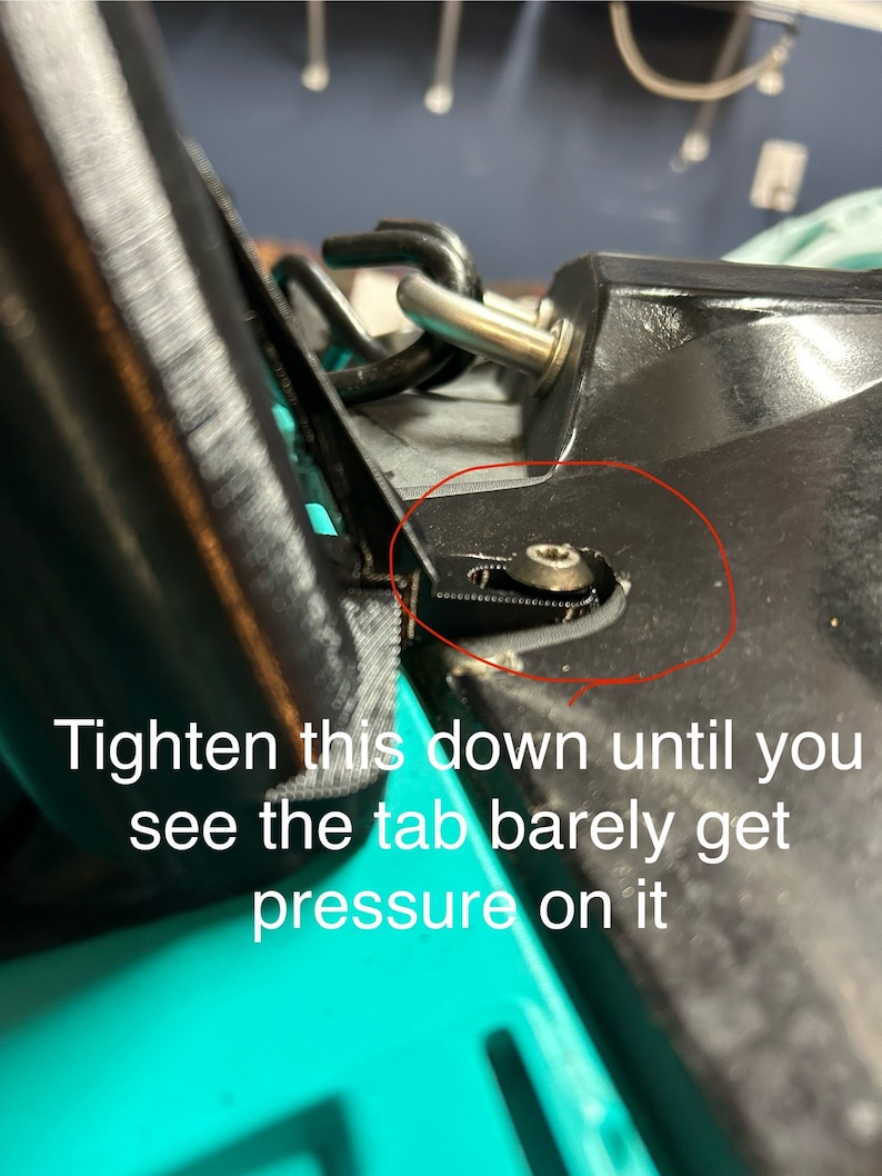 May include: A close-up of a black plastic part with a silver screw. The screw is circled in red. The text 'Tighten this down until you see the tab barely get pressure on it' is visible below the part.
