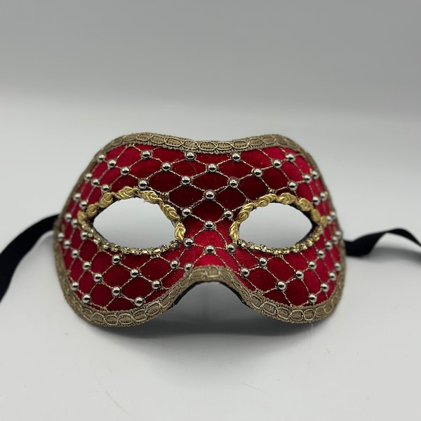 Maskeradeballmaske aus rotem Samt mit goldenem Gitter und goldenen Steinen. Handgefertigte venezianische Maske.