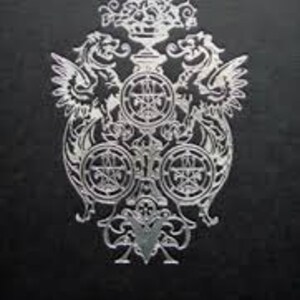 May include: A silver crest featuring two winged dragons flanking a central design. The crest includes a crown, a shield with a cross, and three circular elements with intricate designs. The crest is set against a black background.