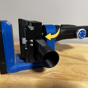 May include: A black and blue pocket hole jig with a drill bit attached. The jig has measurement markings and a rotating blue component. The tool is designed for woodworking and creating pocket holes for joining wood pieces.