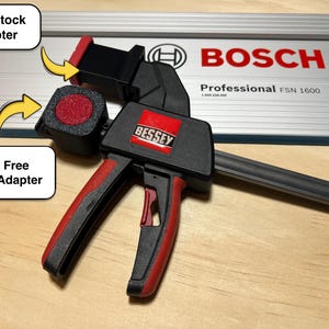 May include: A black and red Bessey clamp with a red handle, positioned over a silver Bosch Professional FSN 1600 track. The image includes a "Thin Stock Adapter" and a "Tool Free Track Adapter".