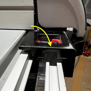 Può includere: Primo piano dei componenti neri e grigi di una sega da tavolo. L'immagine evidenzia la protezione della lama, la guida di misurazione e l'impugnatura. La protezione della lama è nera con un accento rosso, e l'impugnatura è grigia.