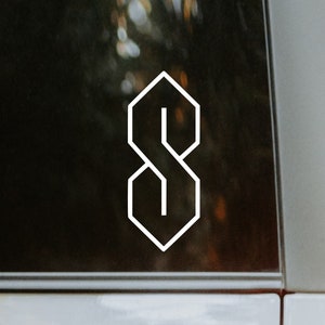 以下が含まれることがあります： スタイリッシュな幾何学的なフォントで書かれた白いアウトラインの文字「S」。「S」は黒い背景の上にあります。