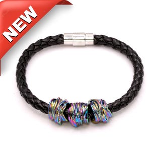 May include: A black leather bracelet with a magnetic clasp and three iridescent metal beads.