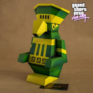 Puede incluir: Una escultura geométrica en tonos verdes y amarillos, con el texto "999" y "Cr". La escultura está inspirada en el videojuego "Grand Theft Auto: Vice City", con el logotipo del juego visible en el fondo.