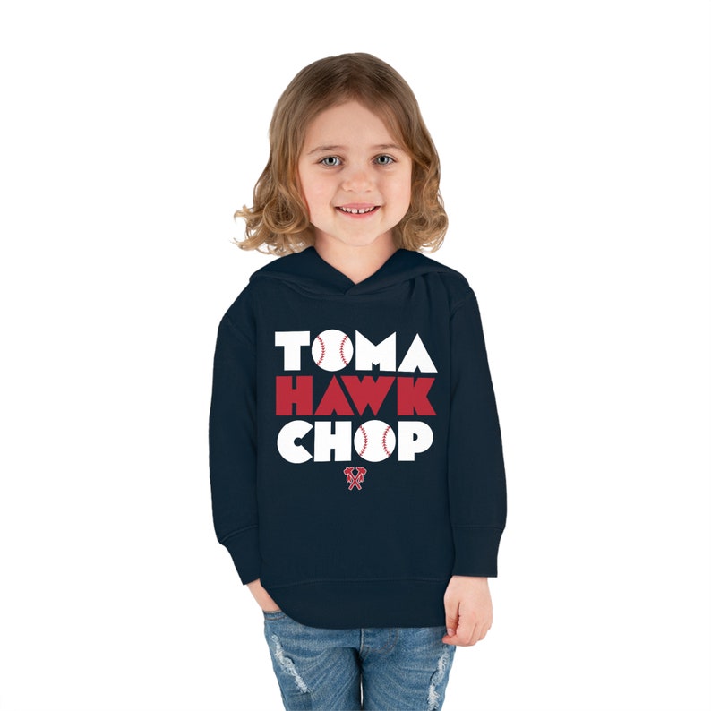 May include: A navy blue hooded sweatshirt with the words "Tomahawk Chop" in white letters with red baseballs in the letters. The logo of the Atlanta Braves is on the bottom of the sweatshirt.