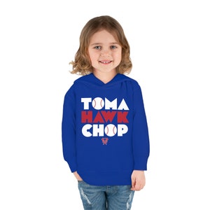 May include: A royal blue hooded sweatshirt with white text that reads "TOMAHAWK CHOP" with a baseball graphic in each letter. The text is in a bold, blocky font.