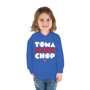 May include: A royal blue hooded sweatshirt with the words "Tomahawk Chop" in white letters with a red baseball graphic in the letters. The word "Hawk" is in red letters. A small red tomahawk graphic is below the text.
