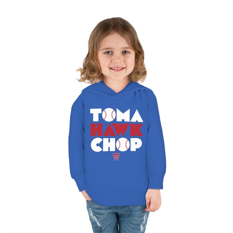 May include: A royal blue hooded sweatshirt with the words "Tomahawk Chop" in white letters with a red baseball graphic in the letters. The word "Hawk" is in red letters. A small red tomahawk graphic is below the text.