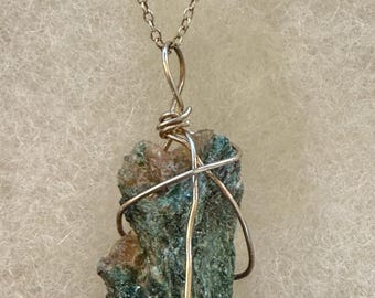 May include: A silver chain necklace with a green and brown stone pendant wrapped in silver wire.