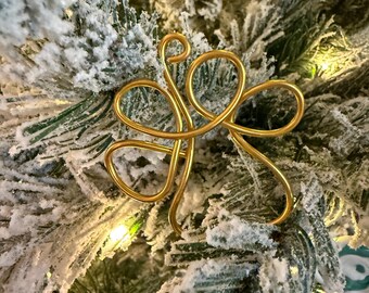 May include: A gold wire ornament shaped like a stylized butterfly, hanging on a snowy artificial Christmas tree.