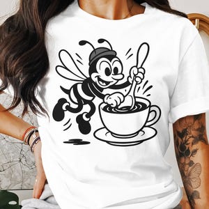 Camiseta con una adorable abeja revolviendo café, divertida para amantes de las abejas, adorable abeja con café, divertida camiseta con una taza de café de abeja.