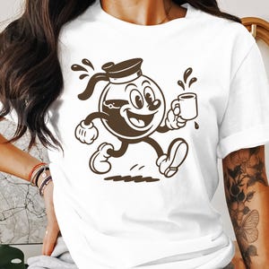 May include: White t-shirt featuring a cartoon coffee pot character with a smiling face, holding a coffee cup. The brown character is running, with coffee splashes and a sailor hat. The design is a vintage-inspired illustration.