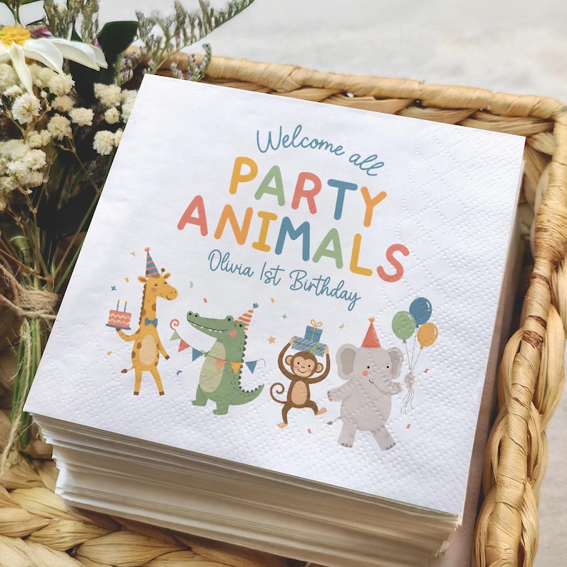 May include: A stack of white square paper napkins featuring a colorful graphic of a giraffe, crocodile, monkey, and elephant wearing party hats. The text reads Welcome all PARTY ANIMALS Olivia 1st Birthday in blue, orange, and red lettering.