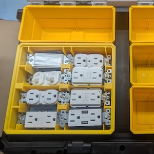 May include: A yellow plastic toolbox with multiple compartments. The compartments contain various electrical outlets and switches.