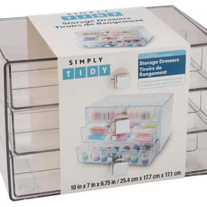 May include: A clear plastic storage unit with three stacked drawers, each featuring a square silver handle. A white paper band wraps around the center, displaying the text Simply Tidy Storage Drawers and dimensions of 10 in x 7 in x 6.75 in.