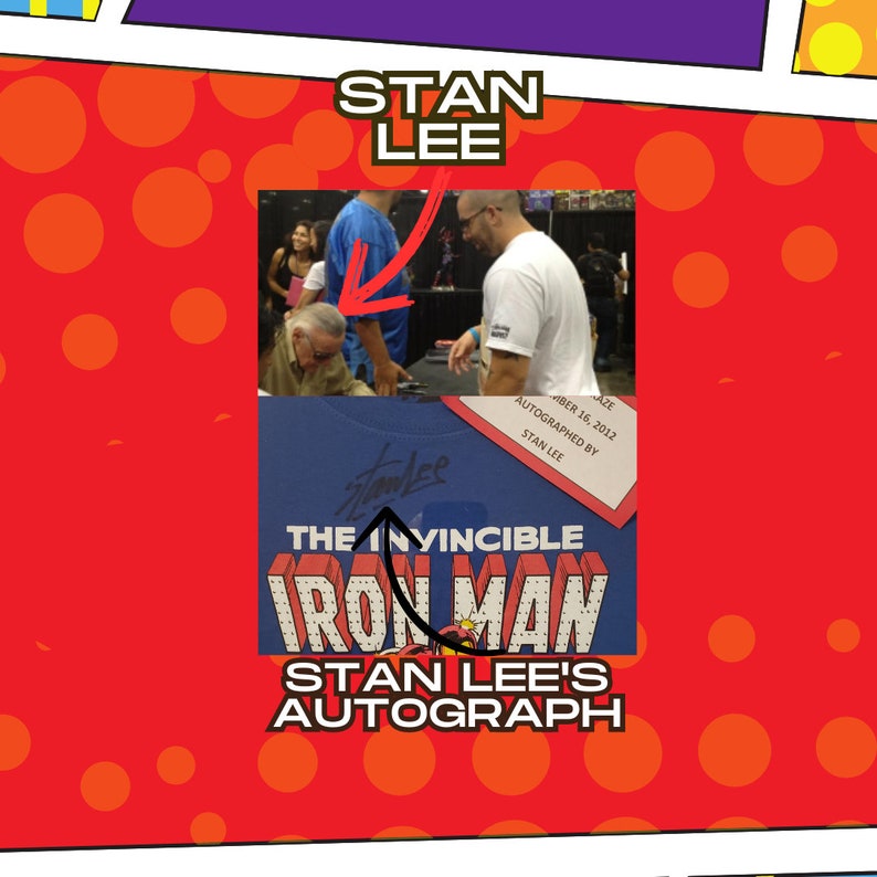 Op de afbeelding: Een blauw T-shirt met een rode, gele en witte afbeelding van Iron Man. Het shirt is gesigneerd door Stan Lee met de tekst "The Invincible Iron Man Stan Lee's Autograph" gedrukt onder de afbeelding.