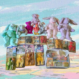 May include: A collection of plush toys and Beanie Babies, including bunnies, bears, and other animals. The toys are in various colors, such as green, pink, purple, and yellow. Some are still in their original packaging.