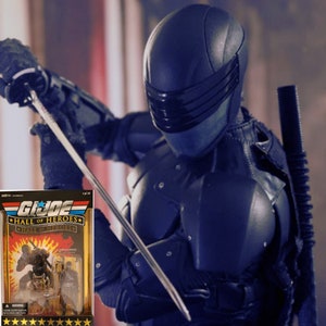 May include: A blue and black action figure of a G.I. Joe character, Snake Eyes, holding a silver sword. The figure is posed in a fighting stance. The figure is packaged in a cardboard box with a G.I. Joe logo and the words "Hall of Heroes".